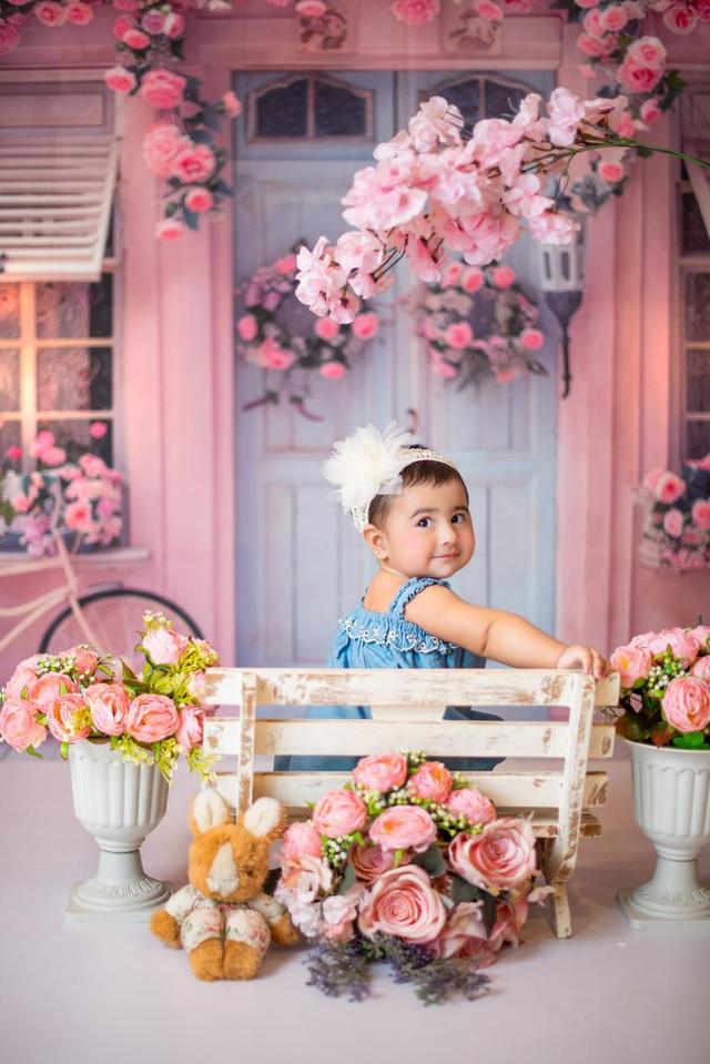 Mahveen in a blue dress surrounded by pink flowers